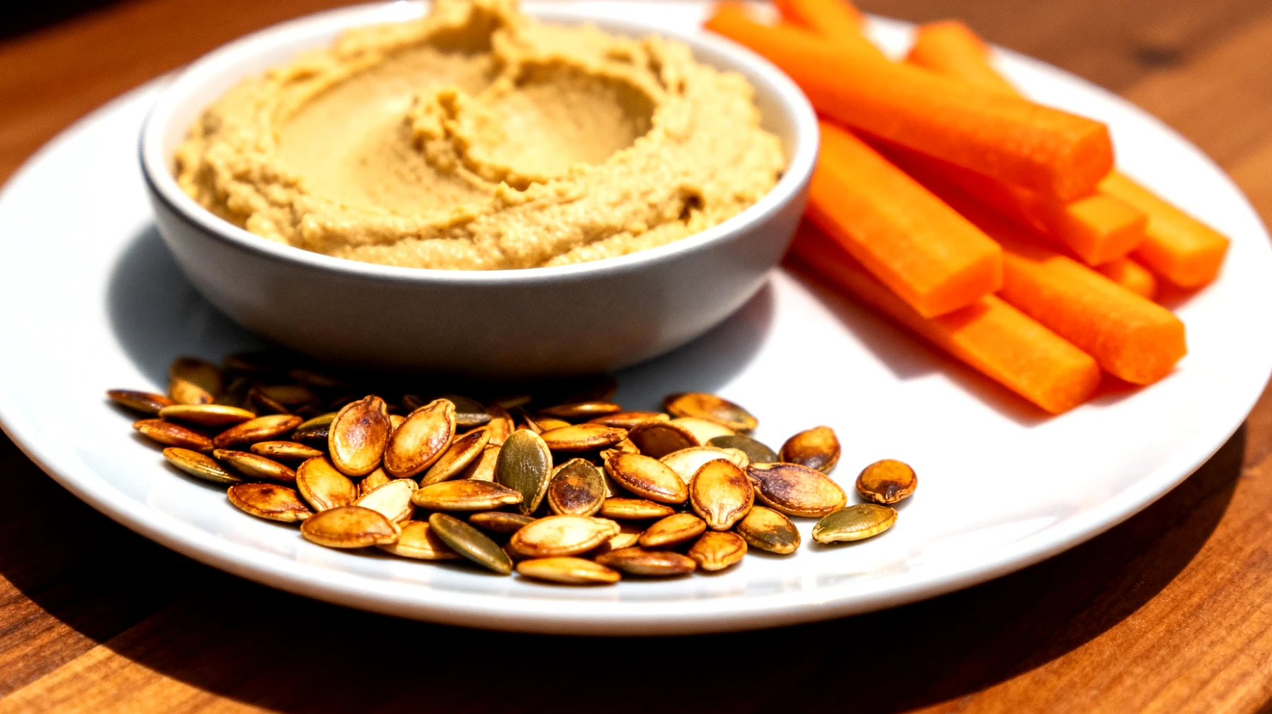 Semi di zucca tostati con carote crude e hummus"